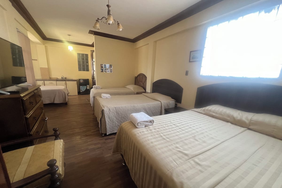 A hotel room with two beds, a wooden dresser, a desk, and a television.