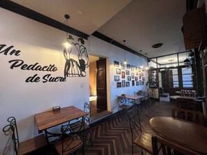 Ein Restaurantinneres mit einer langen Theke, Holztischen und -stühlen. Eine Wand zeigt ein Wandgemälde und gerahmte Bilder.