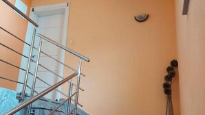 Un escalier avec des rampes en métal et un vase posé sur la plateforme.