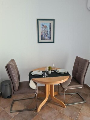 A dining area with a round table for two, two chairs, and a framed picture on the wall.