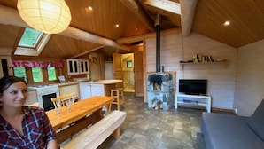 Un intérieur de chalet chaleureux avec une cuisine, un coin repas et une cheminée en pierre.
