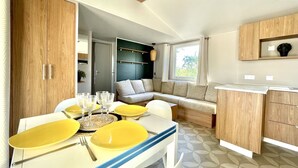 Une cuisine moderne avec des meubles en bois, une table à manger dressée avec des assiettes et des verres jaunes, et un banc intégré agrémenté de coussins.