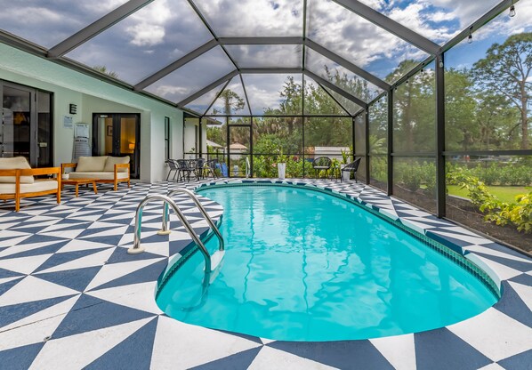 Une piscine couverte ornée d’un motif géométrique en mosaïque, entourée de chaises longues et protégée par une paroi de verre.