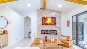 Una sala de estar moderna con chimenea, televisor de pantalla plana y un área de descanso acogedora.
