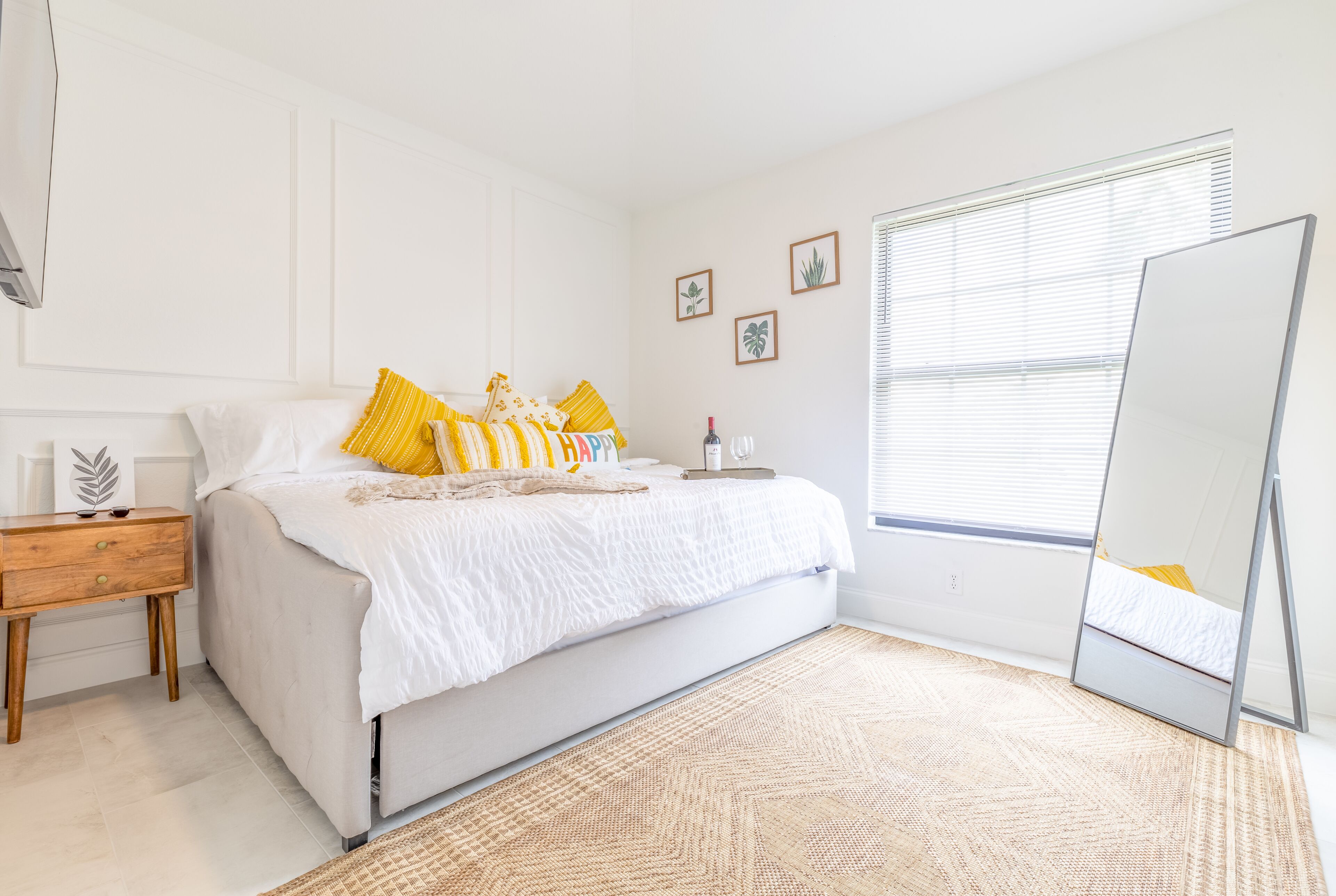 Une chambre à coucher avec un lit, une table de chevet et un grand miroir.