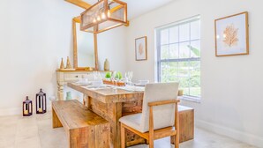 Un área de comedor con una mesa de madera, asientos tipo banco y una lámpara colgante.