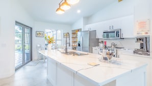 Una cocina moderna con una isla grande, electrodomésticos de acero inoxidable e iluminación colgante.