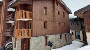 Un edificio de madera de varios pisos, con balcones y muros de piedra.