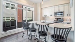 Una cocina moderna con armarios blancos, una isla central y taburetes de bar.