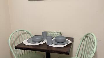 Uma mesa de jantar com duas cadeiras, uma placa na parede e uma cesta.
