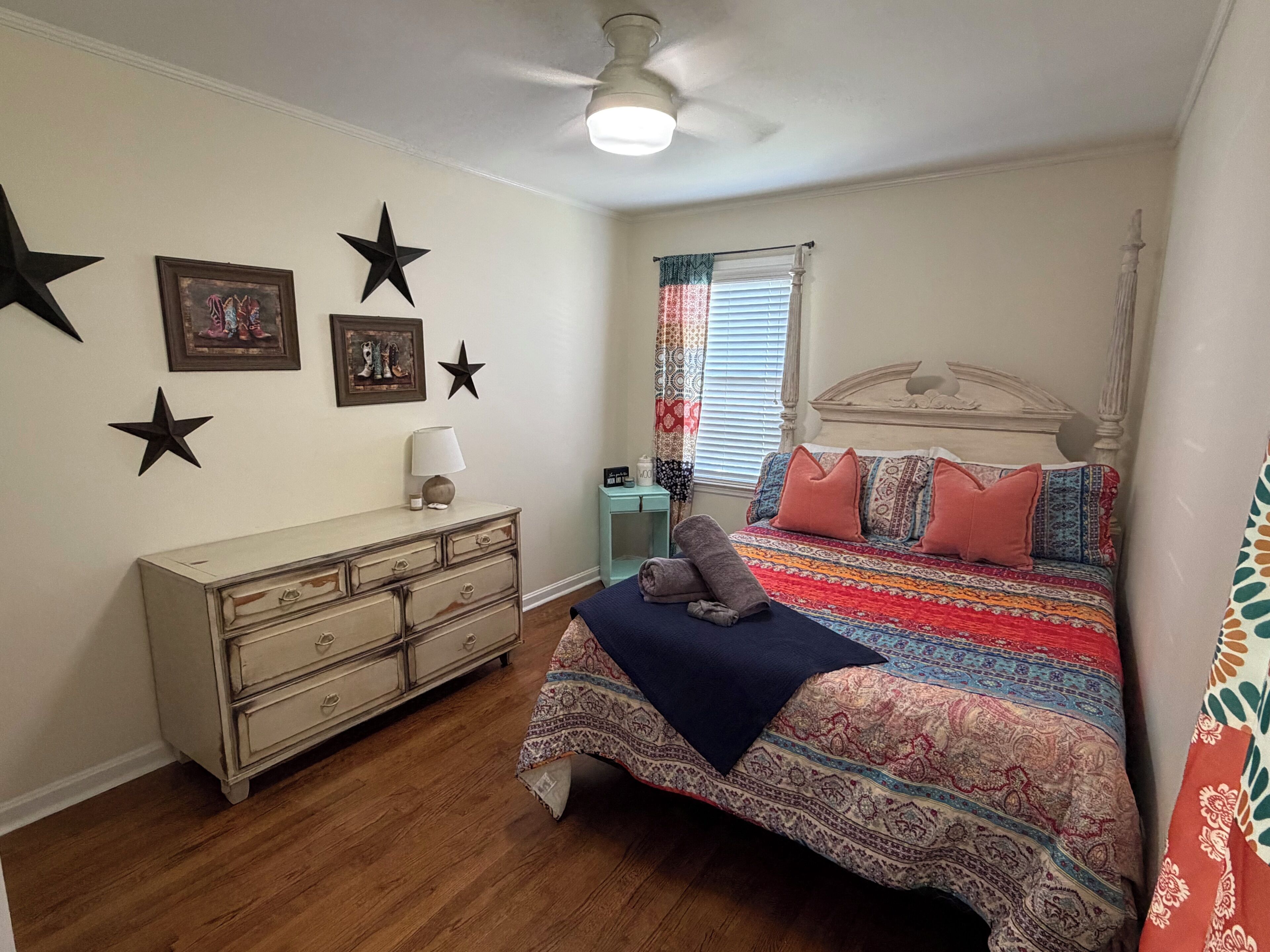 Quarto com cama, cômoda, decorações de estrelas e ventilador de teto.