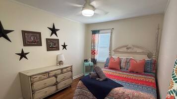 Quarto com cama, cômoda, decorações de estrelas e ventilador de teto.