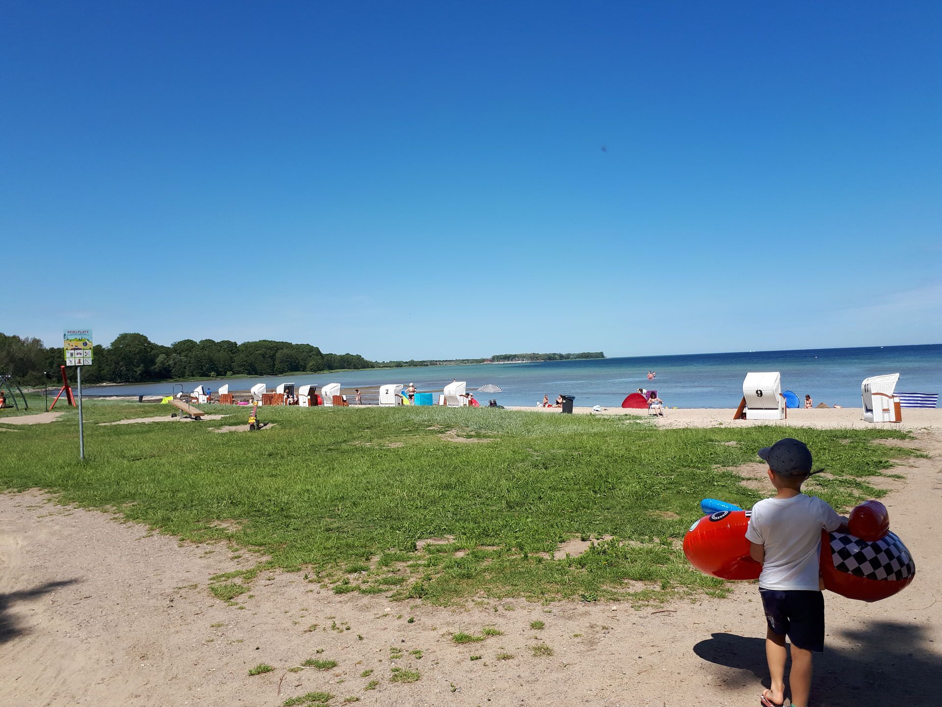 A beach with beach huts and a clear sky.