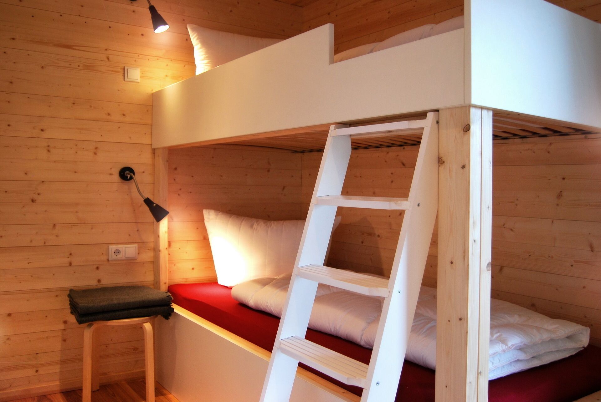 Une chambre avec un lit superposé, une échelle, un bureau et une lampe.