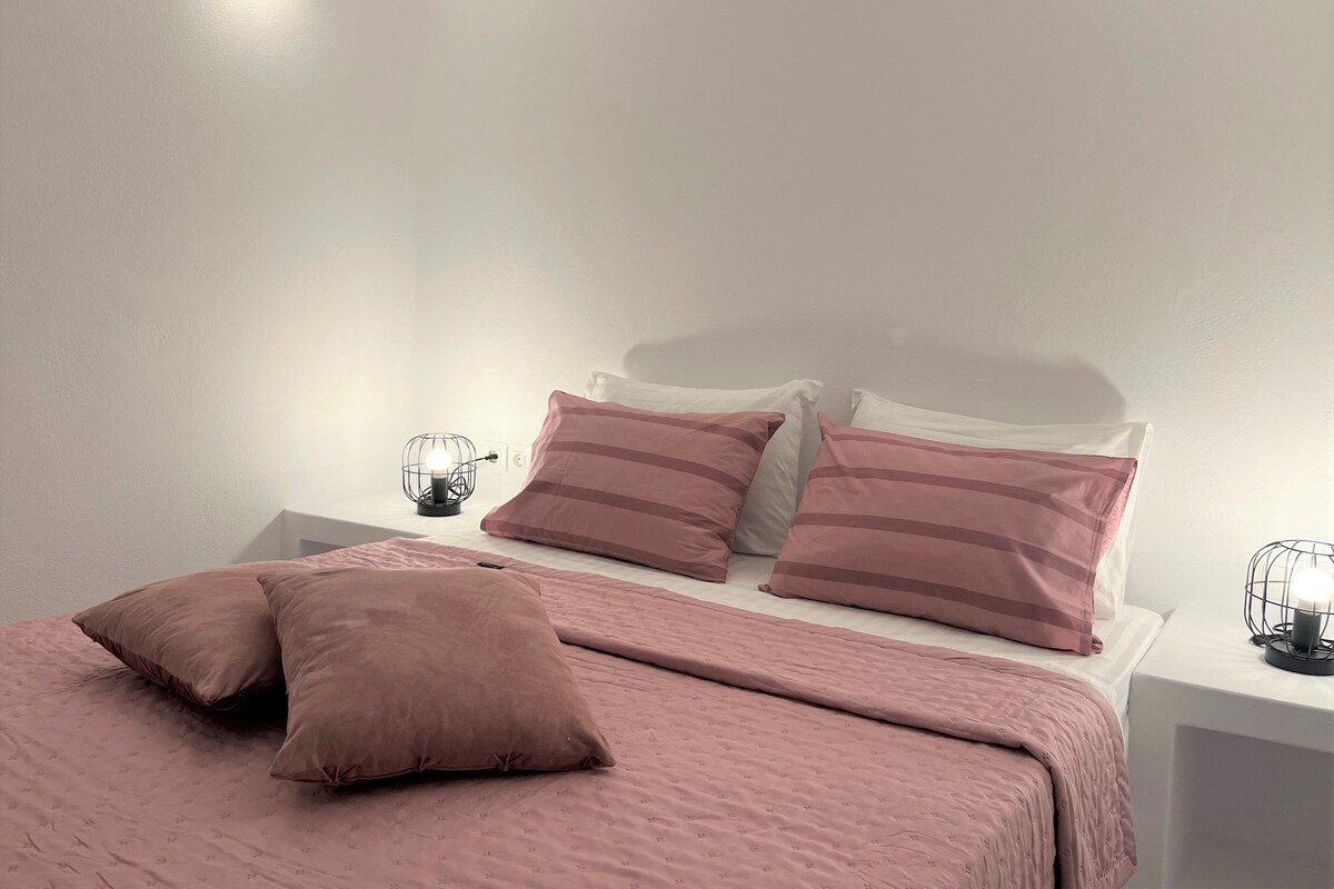 A neatly made bed with pink bedding and two bedside lamps.
