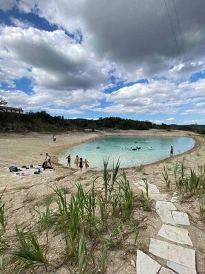 A beach with clear water, people swimming, and a path leading to the water.