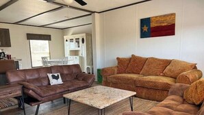 Un salon avec deux canapés en cuir marron, une table basse et un drapeau accroché au mur.