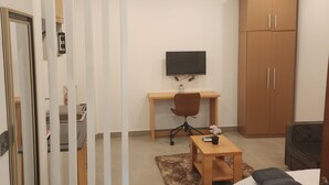 Une chambre à coucher comprenant un lit, un bureau, une chaise, une télévision et une armoire.