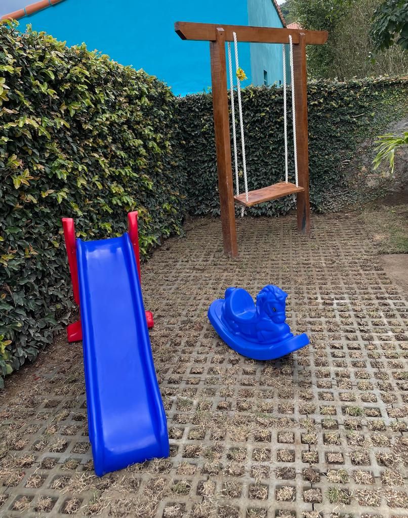 A playground with a blue slide, a swing set, and a blue helmet on the ground.