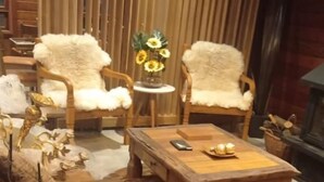 Un salón acogedor con muebles de madera, incluyendo una mesita de centro y sillones, y una planta en maceta.