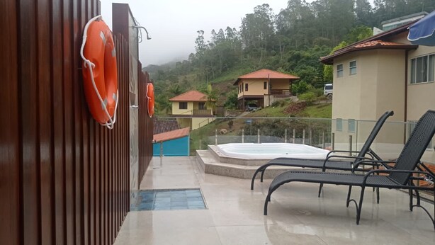 Zona de piscina con sillones de descanso, bañera de hidromasaje y un flotador en una valla de madera.