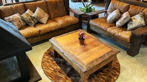 Una sala de estar con una mesa de centro de madera, dos sofás de cuero marrón y un televisor.