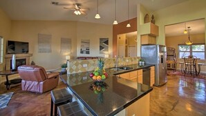 A spacious kitchen with a central island, stainless steel appliances, pendant lighting, and a dining area with a table and chairs.