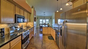 A modern kitchen with stainless steel appliances, wooden cabinets, and a central island.