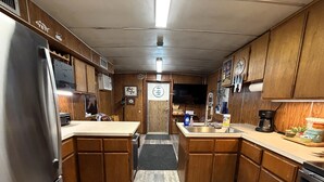A compact kitchen with wooden cabinets, a stainless steel refrigerator, a coffee maker, and a sink. - 6 MAN BEER CAN VENICE MARINA FRONT ROW ICE, WIFI, & W/D GREAT CAMP (Venice)