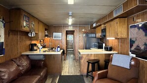 A compact RV interior with a kitchenette, a brown leather couch, a bar stool, and a map on the wall. - 6 MAN BEER CAN VENICE MARINA FRONT ROW ICE, WIFI, & W/D GREAT CAMP (Venice)