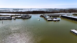 A marina with boats docked, a boat moving through the water, and a large building with a flat roof. - 6 MAN BEER CAN VENICE MARINA FRONT ROW ICE, WIFI, & W/D GREAT CAMP (Venice)