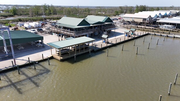 A waterfront property with a dock, covered seating areas, and a building with a green roof. - 6 MAN BEER CAN VENICE MARINA FRONT ROW ICE, WIFI, & W/D GREAT CAMP (Venice)