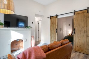 A modern living room with a fireplace, a sofa, a TV, and a sliding barn door. - This townhouse is a 1 bedroom(s), 1 bathrooms, located in Wichita, KS. (Wichita)