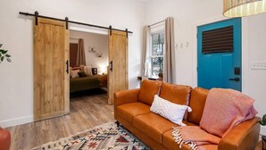 A modern living room with a sliding door leading to a bedroom, a blue door, and a brown leather sofa. - This townhouse is a 1 bedroom(s), 1 bathrooms, located in Wichita, KS. (Wichita)