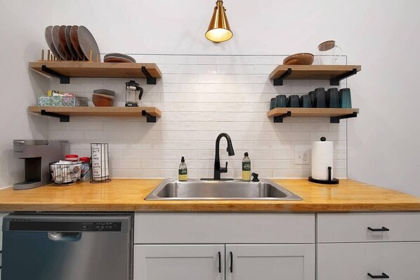 A modern kitchen with a stainless steel sink, wooden countertops, and built-in shelves for storage. - This townhouse is a 1 bedroom(s), 1 bathrooms, located in Wichita, KS. (Wichita)