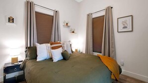 A bedroom with a bed, pillows, a nightstand, a lamp, a wall-mounted shelf with decorative items, and a framed picture on the wall. - This townhouse is a 1 bedroom(s), 1 bathrooms, located in Wichita, KS. (Wichita)