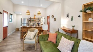 A spacious living area with a green sofa, wooden chairs, a dining table, and pendant lights. - This townhouse is a 1 bedroom(s), 1 bathrooms, located in Wichita, KS. (Wichita)