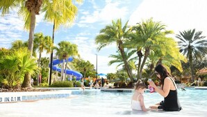 A pool area with palm trees, a water slide, and people swimming. - Holiday Inn Vacation club Orange Lake (Kissimmee)