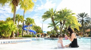 Une zone de piscine agrémentée de palmiers, d’un toboggan aquatique et de personnes qui se baignent.