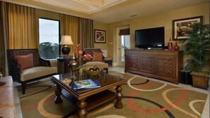 A hotel room with a sofa, armchair, coffee table, TV, and a large window with curtains. - Holiday Inn Vacation club Orange Lake (Kissimmee)