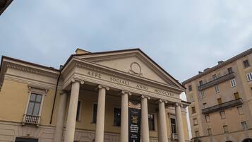 Un edificio neoclassico con colonne, un timpano e uno striscione che indica un anniversario di un teatro sociale.