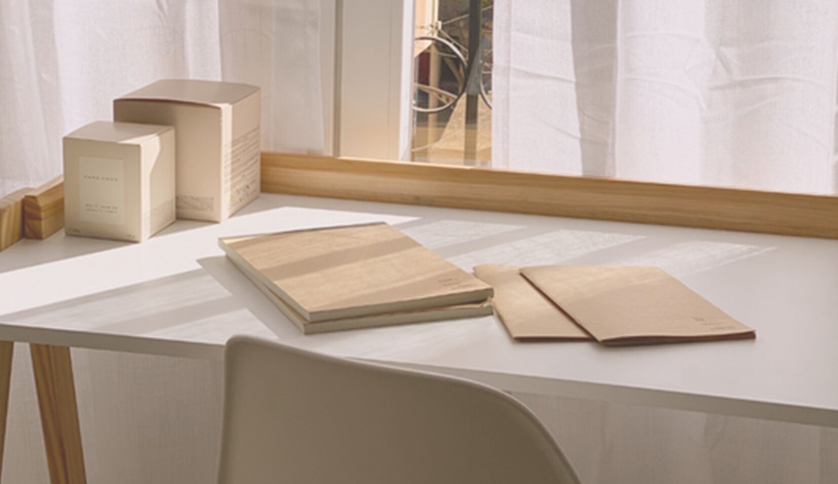 A white desk with a wooden chair, a box, and two notebooks.