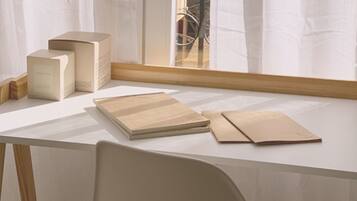 A white desk with a wooden chair, a box, and two notebooks.