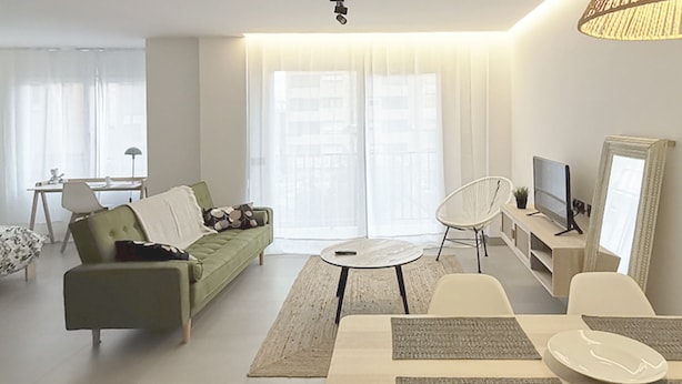 Una sala de estar moderna con un sofá verde, una mesa redonda de centro y un mueble para la televisión.