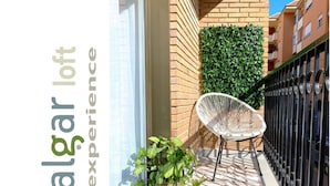 Un balcón con una silla blanca, una planta en maceta y un piso con diseño.