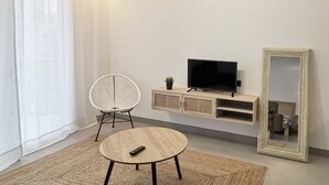 A modern living room with a round table, a white chair, a television on a wooden stand, and a large mirror. - Premiere lotf algar air-conditioned!!! If you're hot, it's because you want to!  (Callosa de Ensarriá)