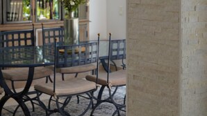 Un coin repas comprenant une table en verre, des chaises et un buffet aux portes vitrées.