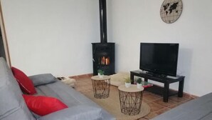 Ein Wohnzimmer mit einer Couch, einem Fernseher, einem Kamin und zwei Beistelltischen.