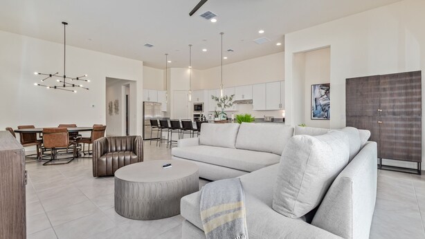 A spacious living room with a large sofa, a coffee table, and a dining area with chairs and a table. - Cave Creek Gem! New Construction! (Cave Creek)