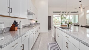 A modern kitchen with white cabinetry, granite countertops, and stainless steel appliances. - Cave Creek Gem! New Construction! (Cave Creek)